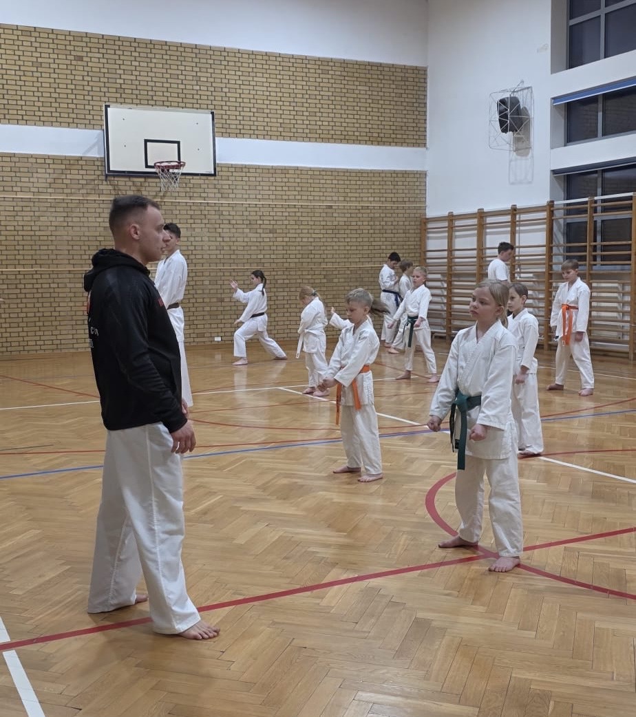 Trener prowadzący trening karate z grupą dzieci w hali sportowej Raion Fight Club